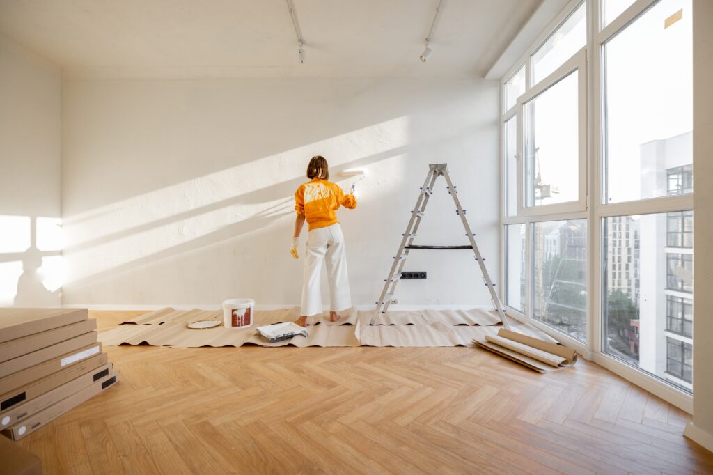 Woman paints wall, renovating her apartment